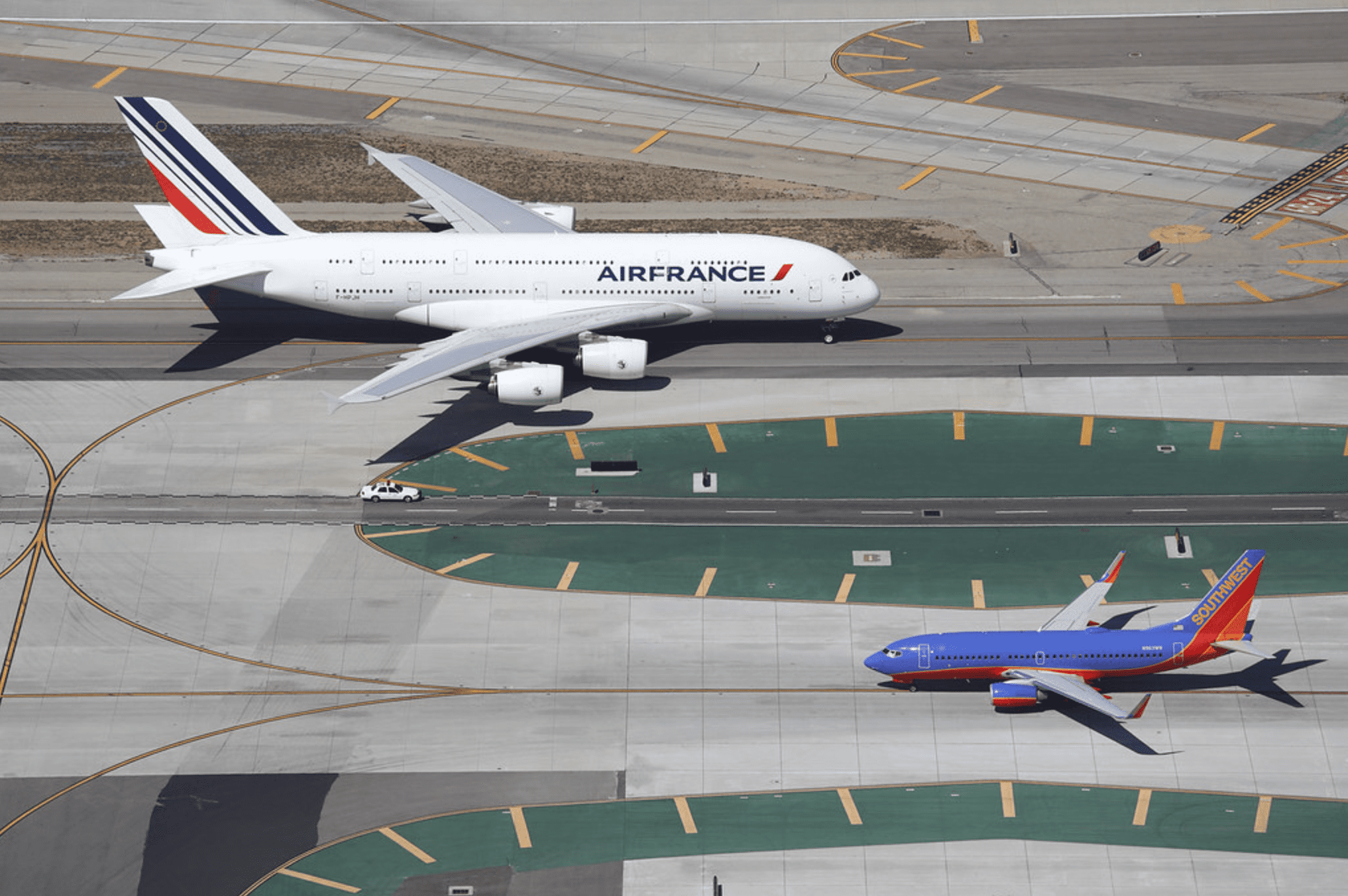 Máy bay 2 tầng A380 của Air France chạy ngược chiều Boeing 737-700 của Southwest Airlines trên đường băng sân bay quốc tế Los Angeles, Mỹ. Để tưởng tượng về kích thước thực của máy bay, hãy so sánh với chiếc ôtô Ford Crown Victoria ở giữa. Ảnh: Steve Arthur/Flickr